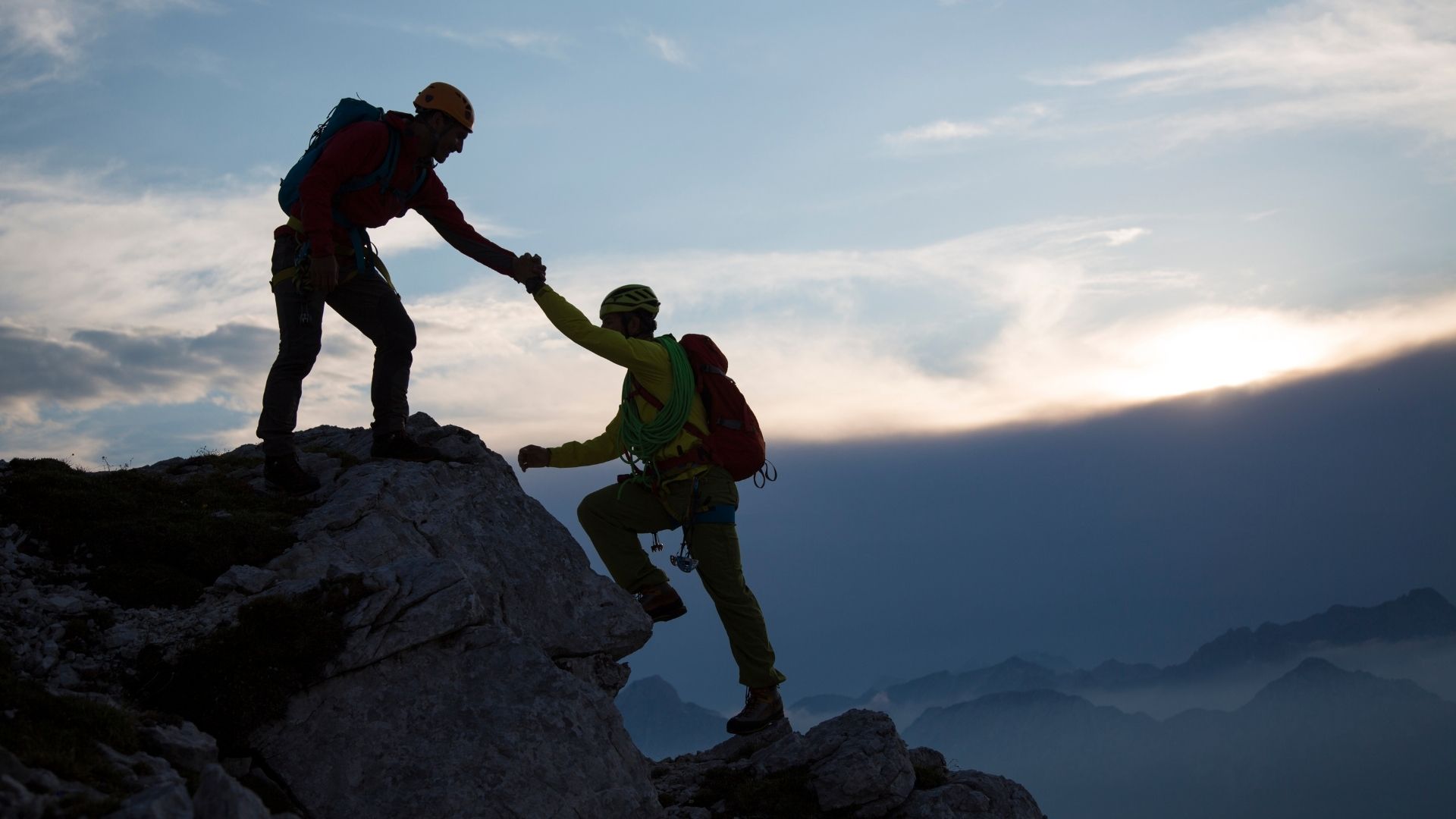 climber helping another one climb a rock