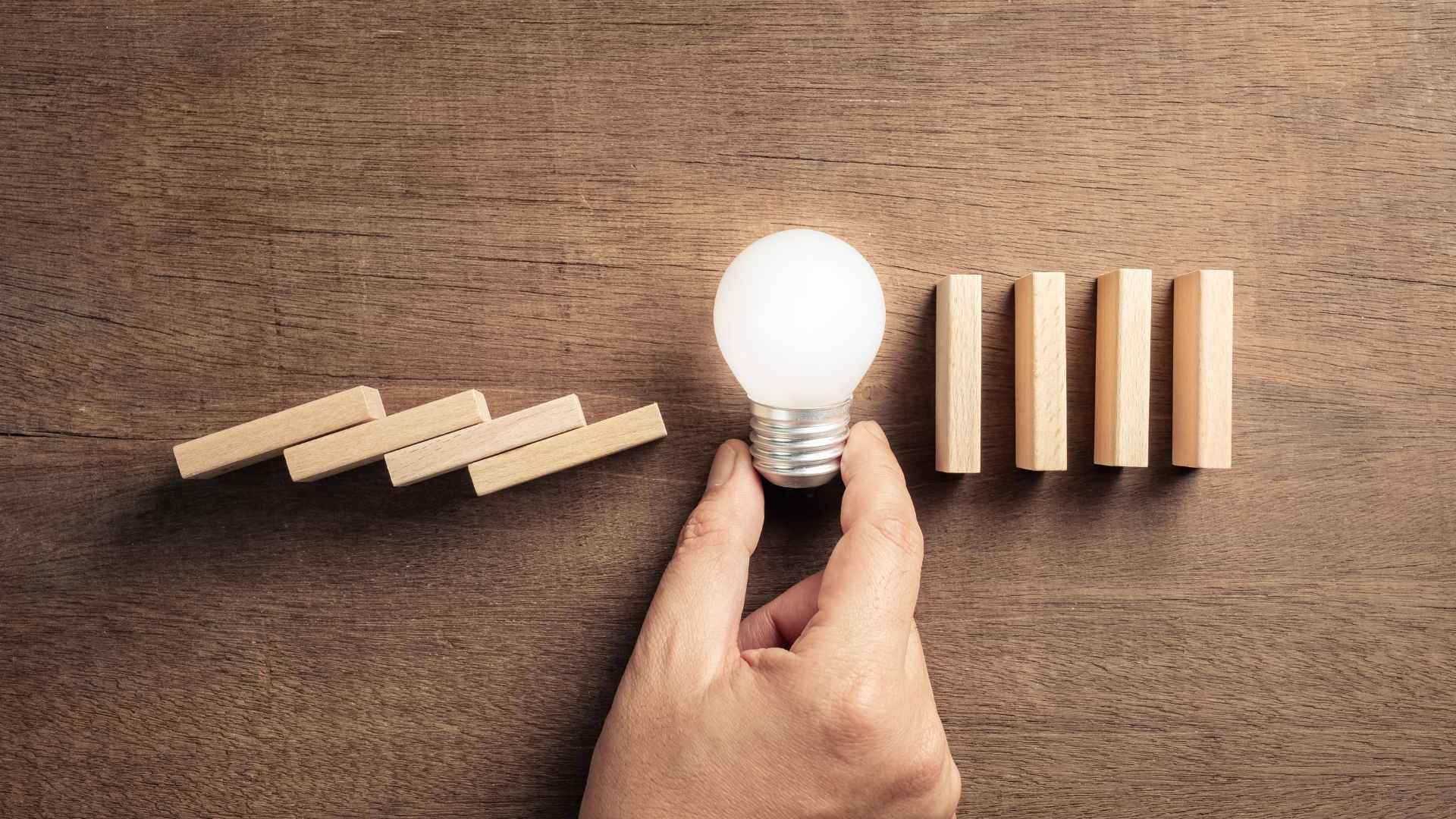 domino blocks and a hand holding a bulb symbolizing prevention