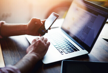 Person using phone and laptop