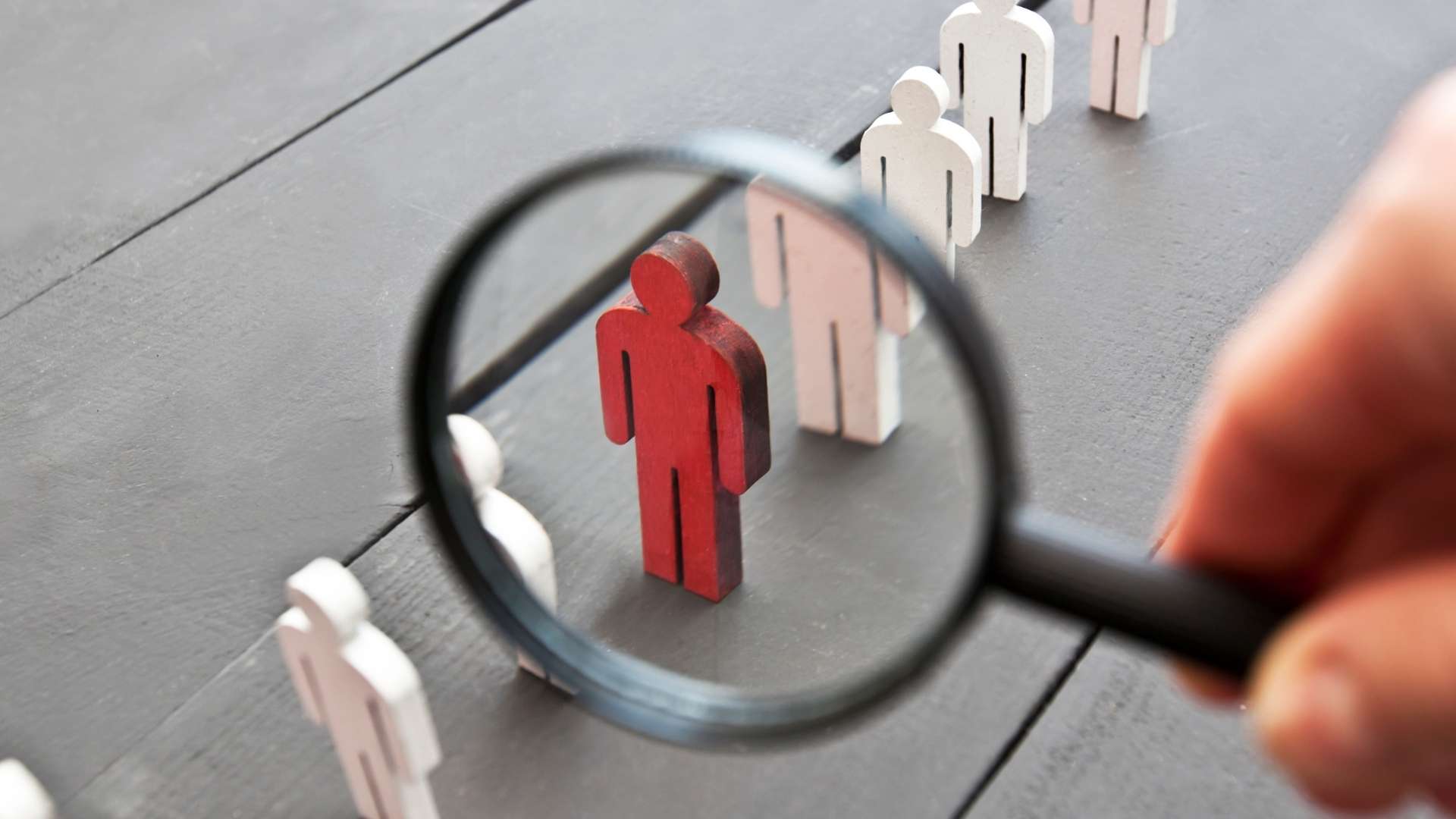 The view through the magnifier on the one wooden red person between other people