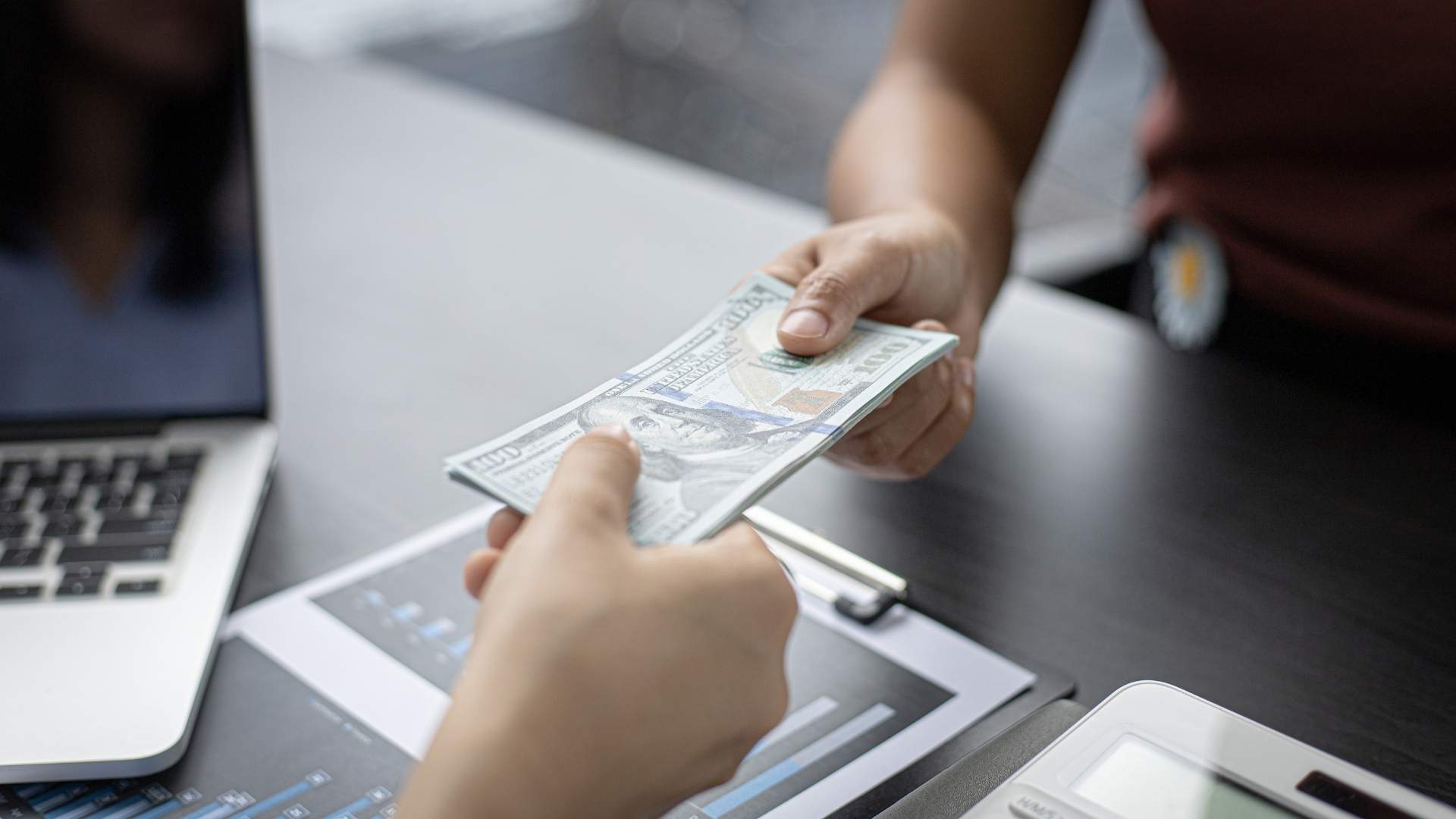 two people holding a dollar bills