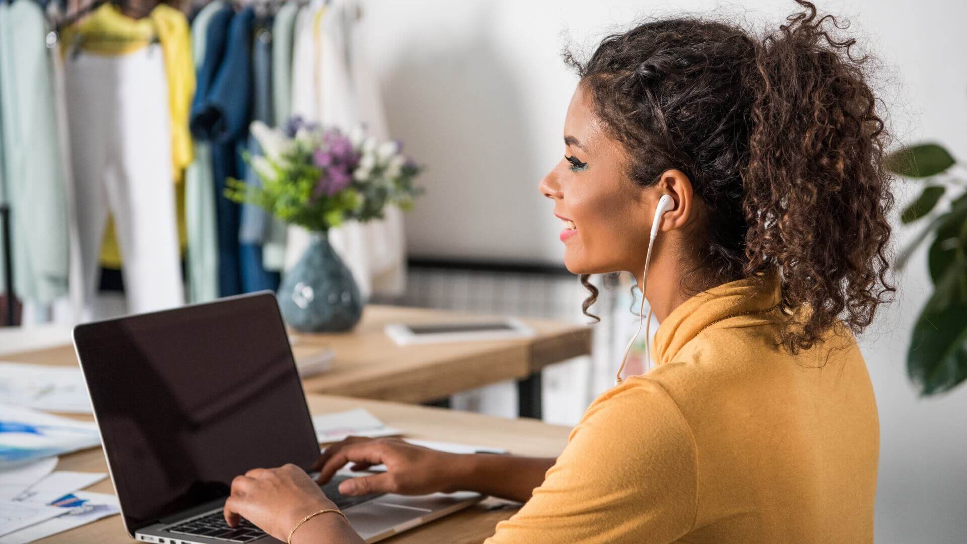 Woman wearing yellow sleves using a laptop while listening Music