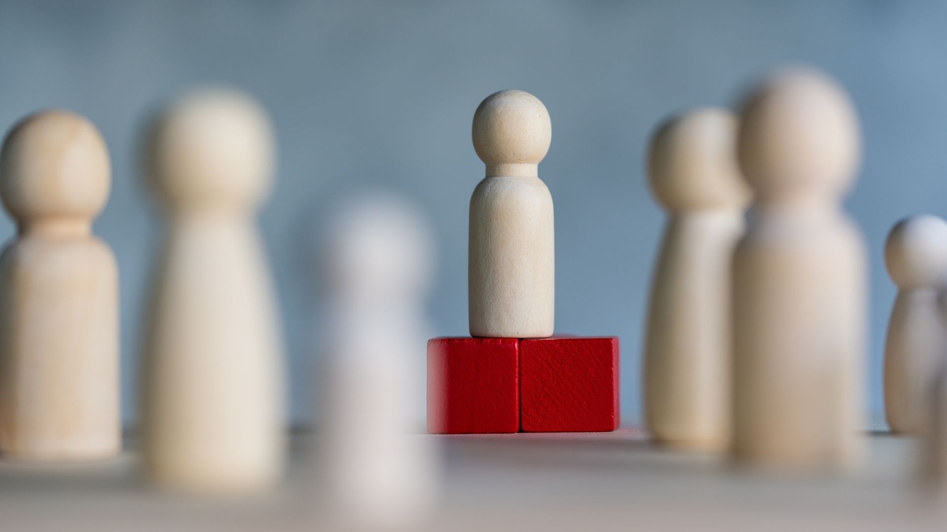 Wooden figures and peg dolls standing on the red podium