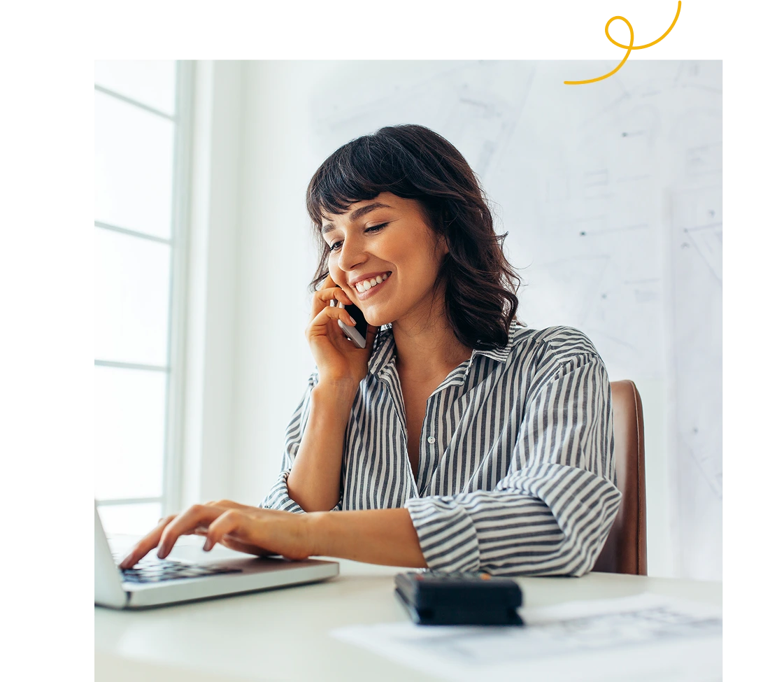 A woman talking to someone while using a laptop