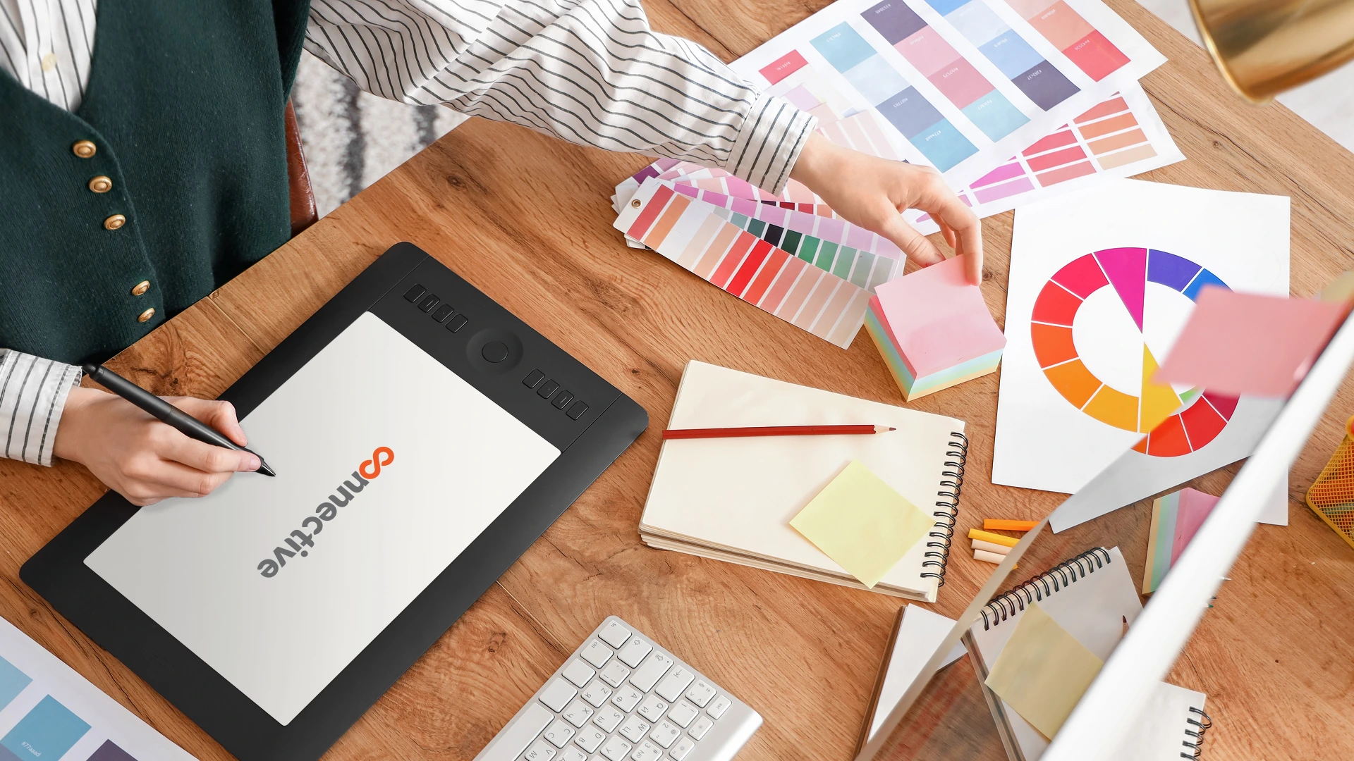 Female graphic designer working with tablet on table in office, top view