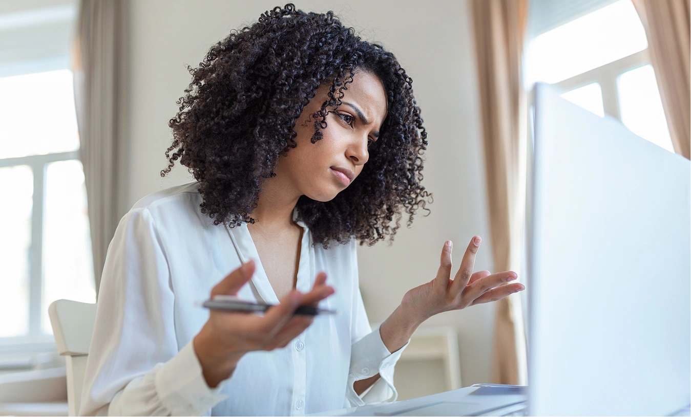 Frustrated woman looking at her laptop while holding a phone